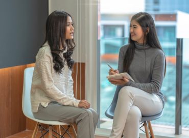Asian woman professional psychologist doctor giving the consult to female patients in modern living room of house or hospital exam room, Mental health Concept