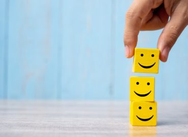 smile face on yellow wood cube. Service rating, ranking, customer review, satisfaction and emotion concept.